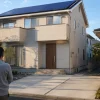 太陽光付き戸建てでEV・V2H導入前の空いた駐車場を見渡す住宅所有者